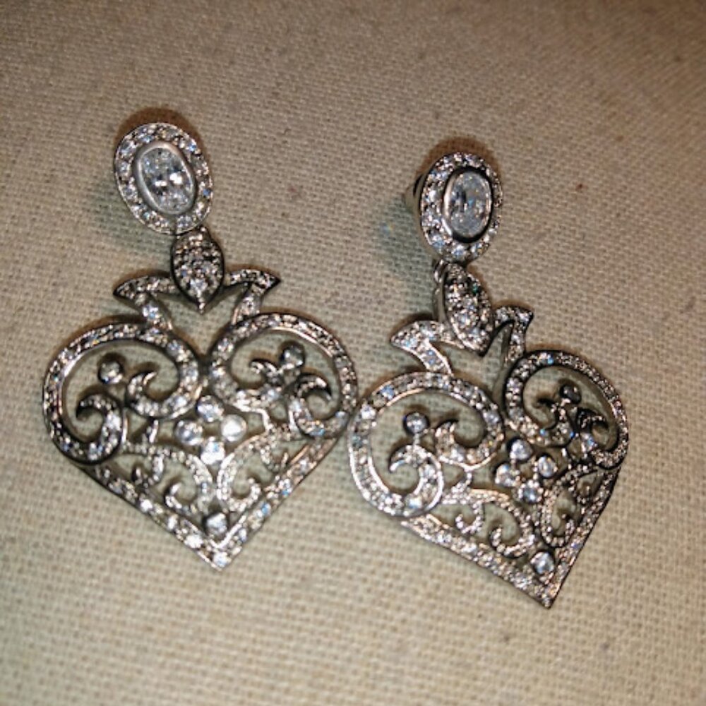 Heart shaped silver tone dangle push back earrings with clear stones.